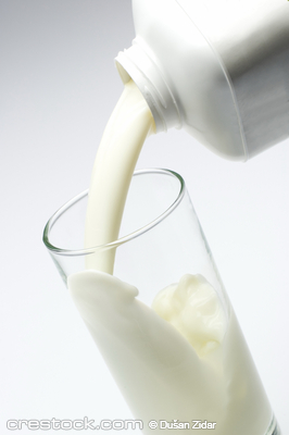 white milk pouring from bottle into a glass